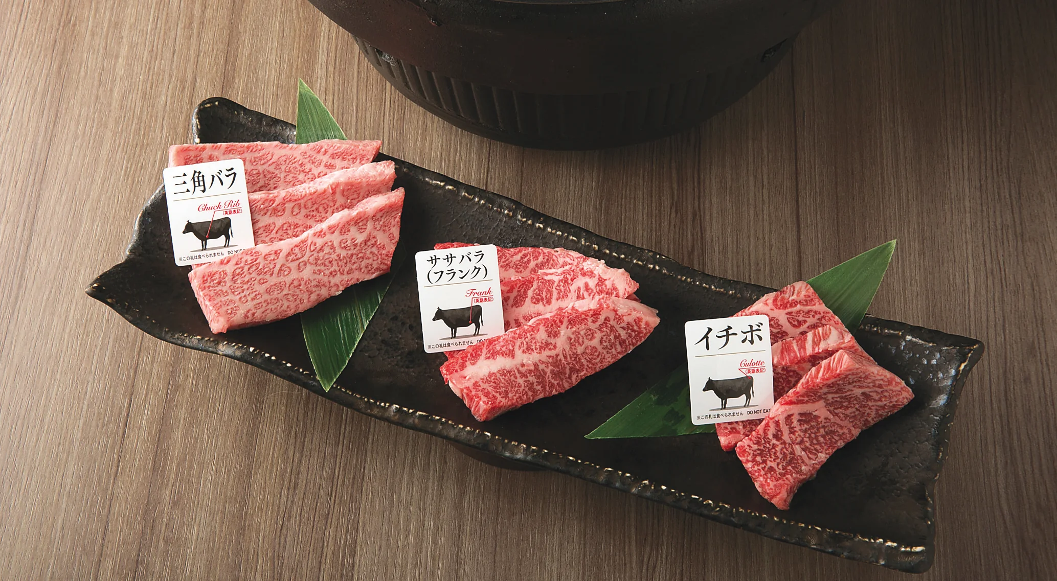An assorted yakiniku platter presented with bilingual meat-cut tags